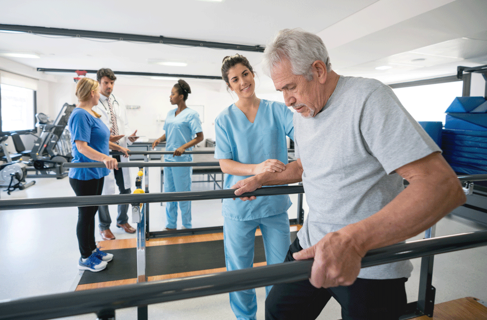 Provider standing next to patient as he uses parallel bars